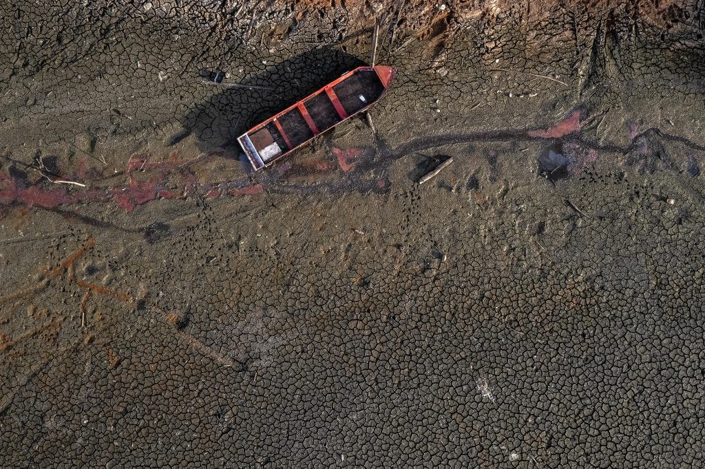 A boat stranded on cracked, dried-out earth after water levels collapsed