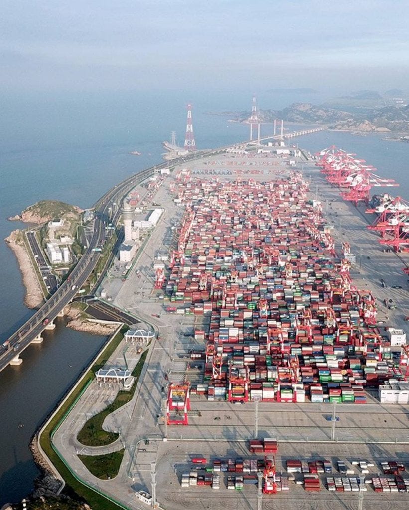 Aerial view of a vast container port with stacked shipping containers and cranes