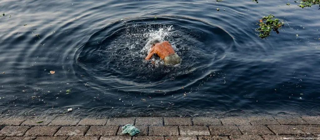 A man bathing in river water contaminated by textile dyeing effluents