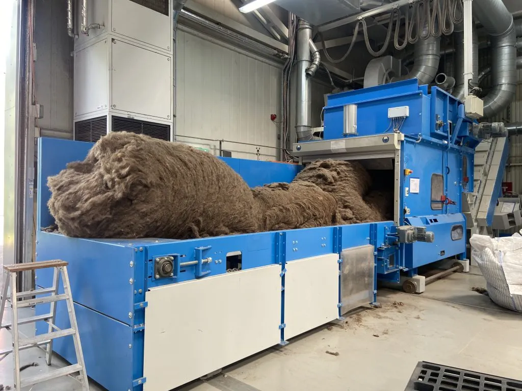 Bales of raw hair waste being fed into processing machinery
